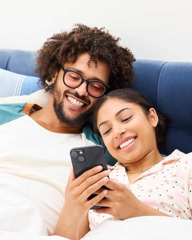 Ein Paar entspannt im Bett und schaut auf ein Smartphone