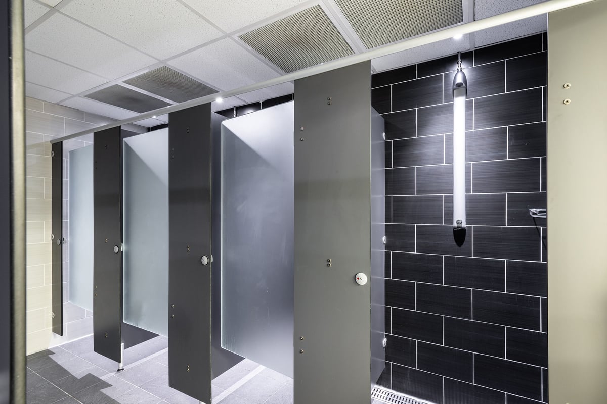 PureGym Northwich: Shower stalls, black tiled wall, stainless steel appearance.
