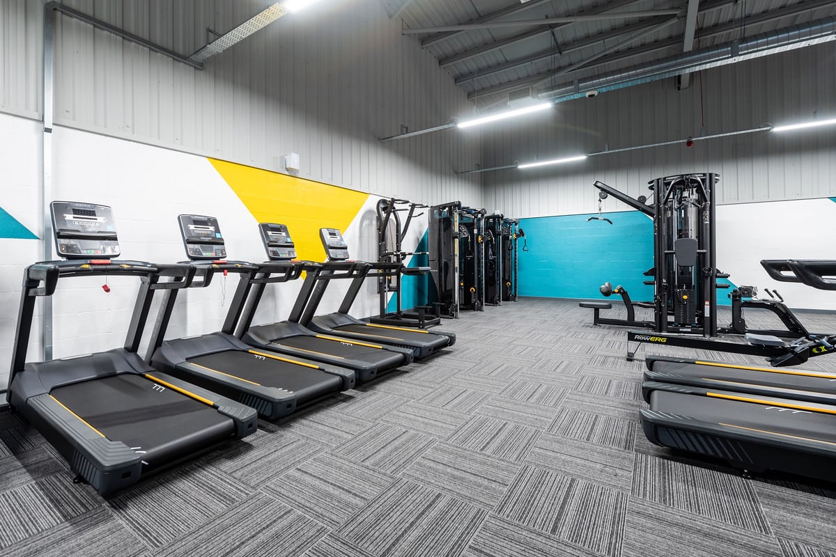 PureGym Alfreton: Rows of treadmills, cable machines, and weightlifting stations in a brightly lit gym interior.