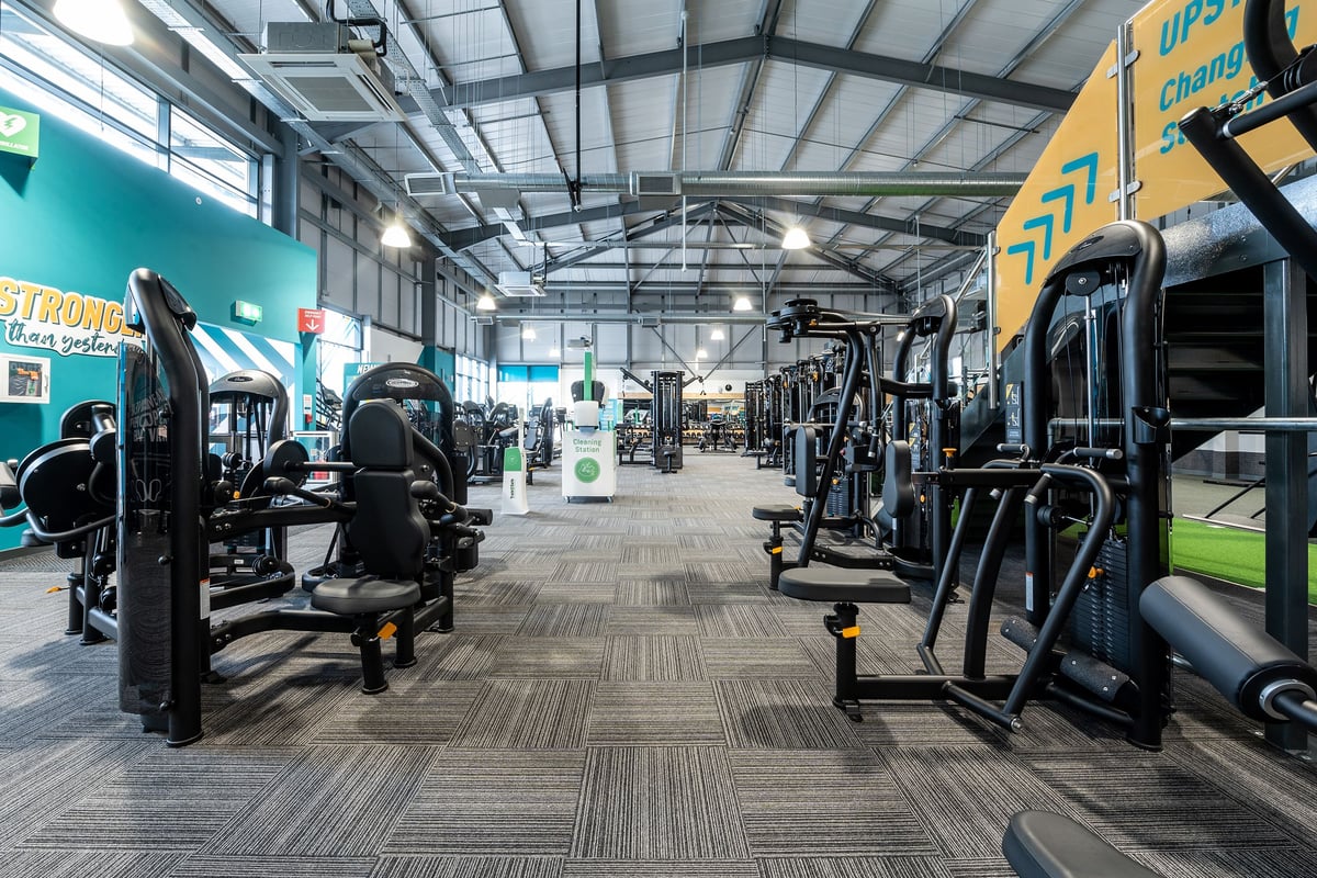 PureGym Cirencester: Rows of resistance machines, free weights, benches, and circuit equipment in a brightly lit gym.