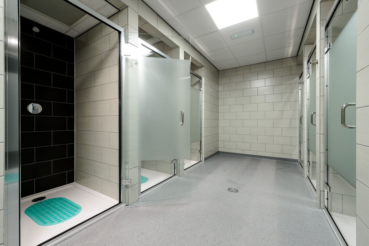 PureGym Glasgow Hope Street: Shower area with tile walls, floor drain, and cubicle stalls.