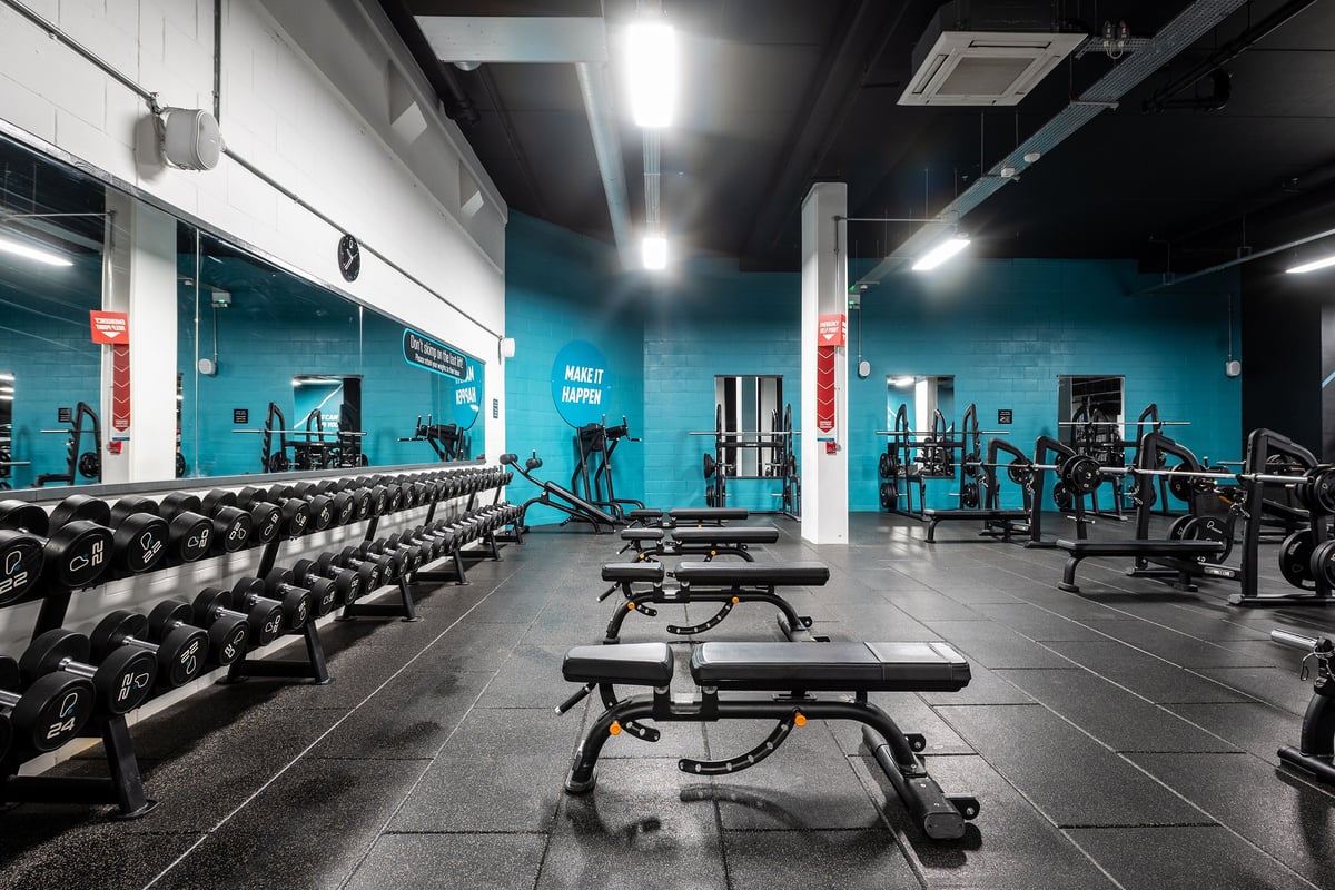 PureGym Norwich Castle Mall: Weight benches, dumbbells, racks with weight plates, blue walls, mirrors, rubberized flooring.