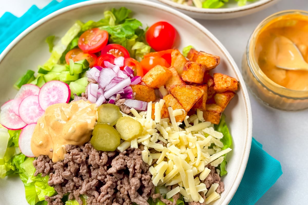 Bowl of salad with seasoned mince, lettuce, tomatoes, gherkins, cheese and dressing
