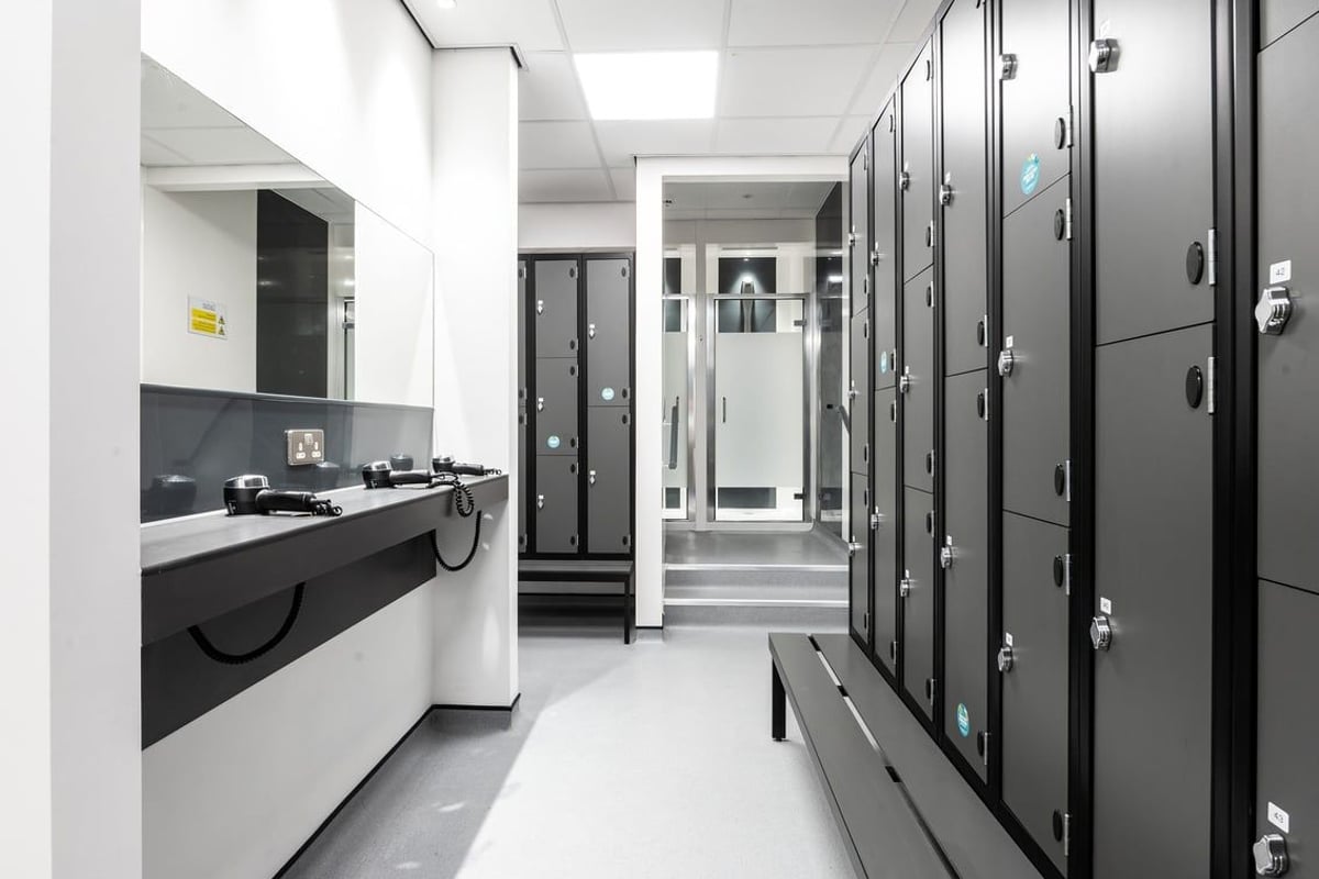 PureGym Cirencester: Rows of grey lockers, sink counter, and tiled floors - appears to be a changing room facility.