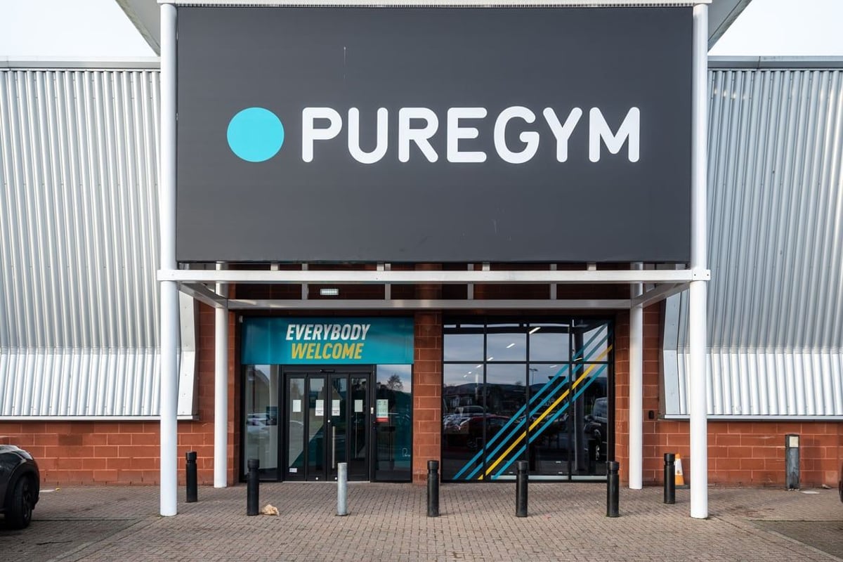 PureGym Lanark: PureGym exterior with signage, entrance doors, and exercise equipment visible inside.