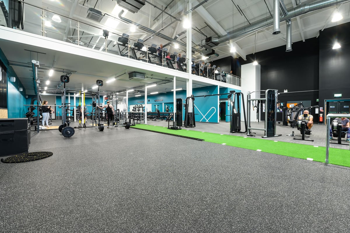 PureGym Exeter Bishops Court: Weight racks, resistance machines, rubberised flooring, and mirrored walls in a modern gym studio.