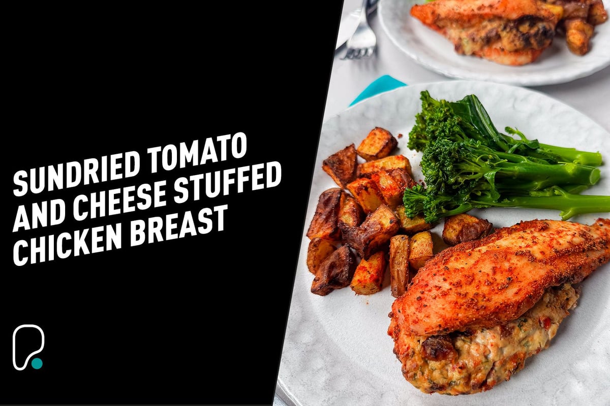 Stuffed chicken breast with roasted potatoes and steamed broccolini on a white plate