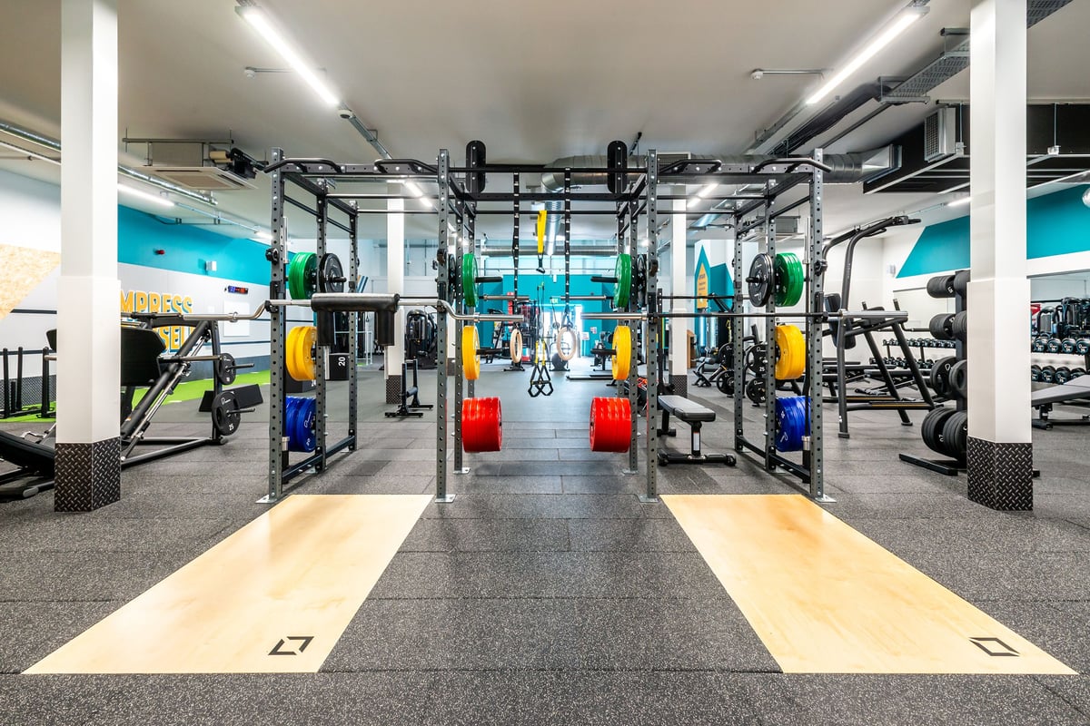 PureGym Market Harborough: Functional training rig, weight plates in multiple colours, rubberized floors, wall graphics.