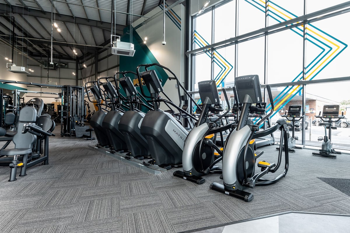 PureGym Nottingham West Bridgford: Rows of stationary bikes and elliptical machines in a modern fitness studio.