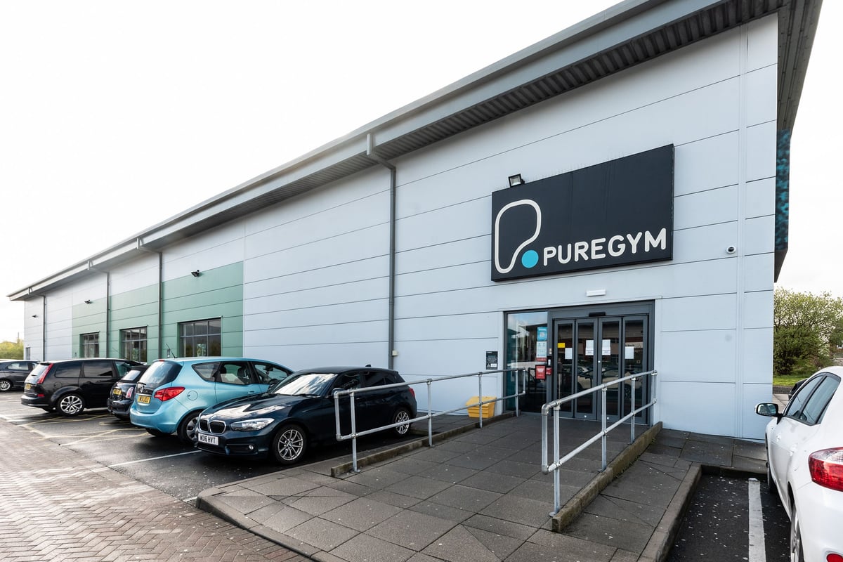 PureGym Widnes: Gym exterior with parking spaces and signage displaying "Pure Gym" logo.