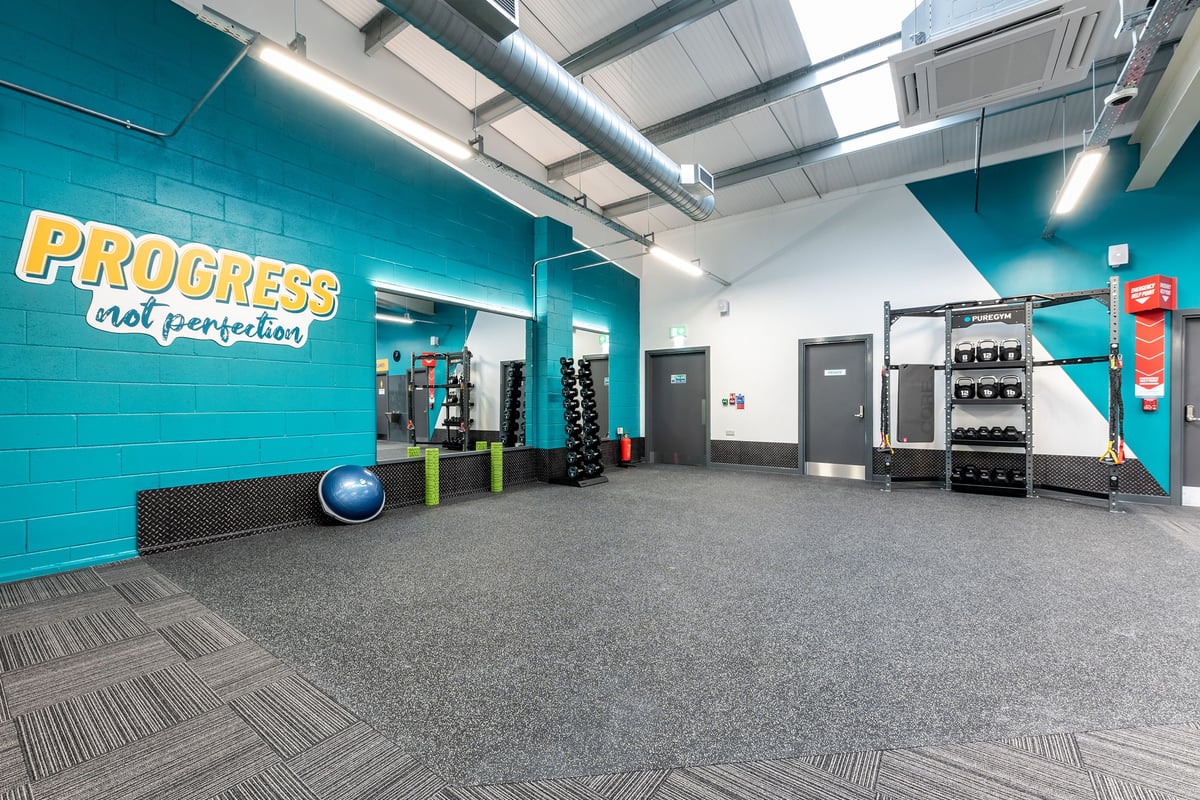 PureGym Consett: Exercise machines, resistance equipment, rubberized floors, and teal accent walls.