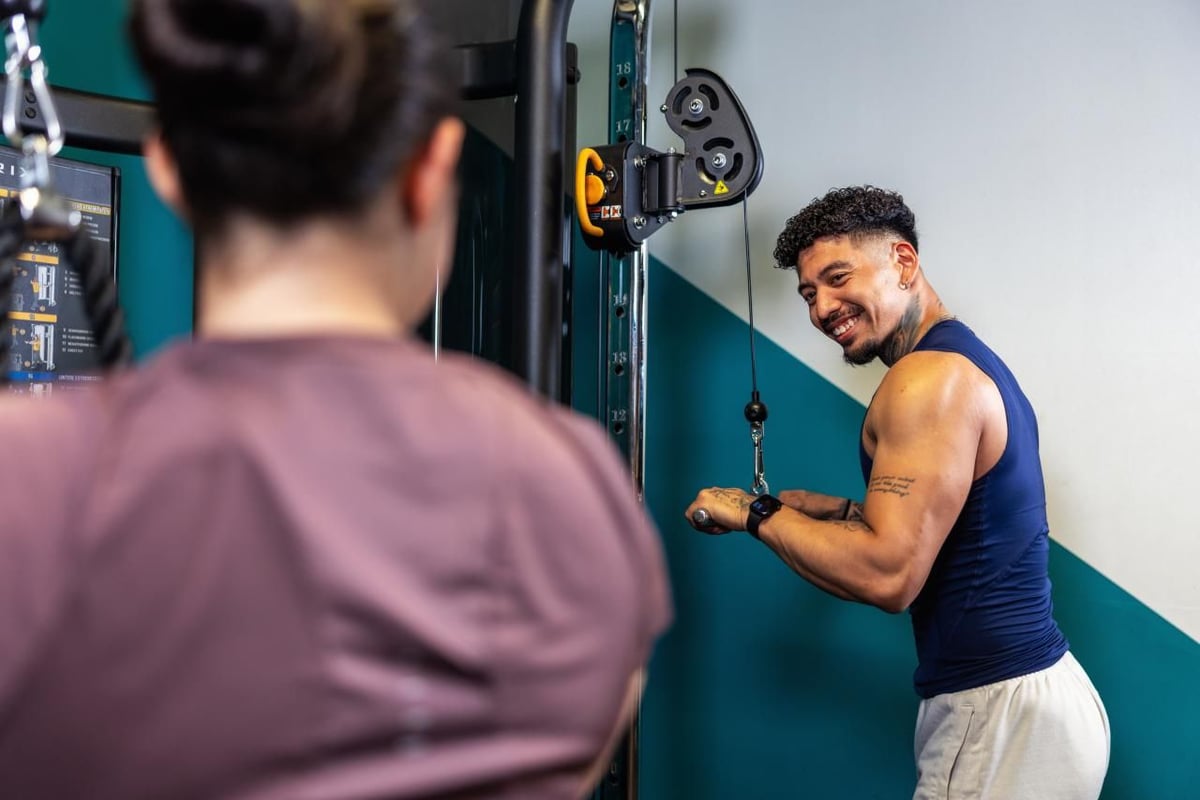 Smiling PureGym member using a cable pull-down
