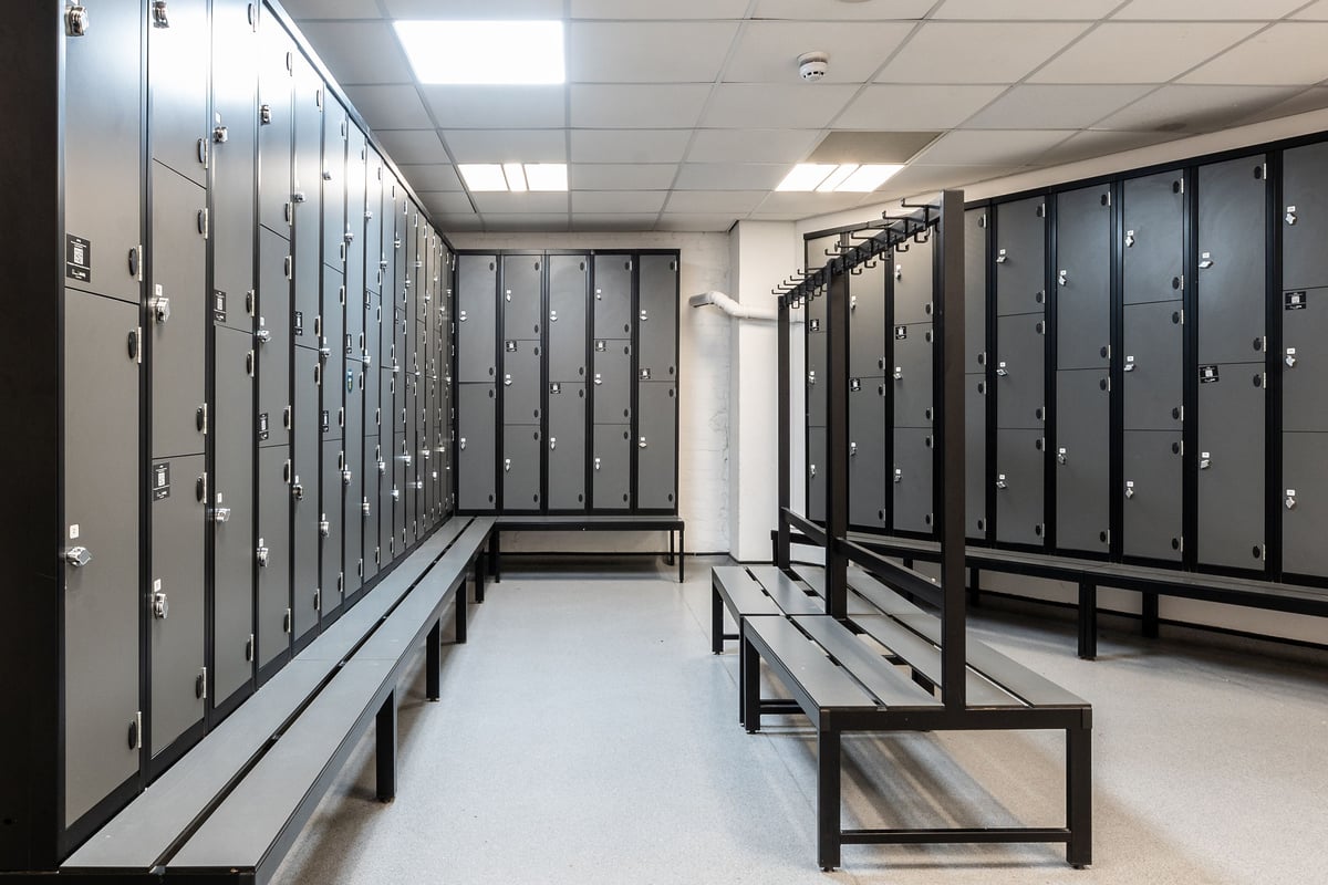 PureGym Bristol Union Gate: Rows of lockers, benches, and an aisle in a changing room setting.