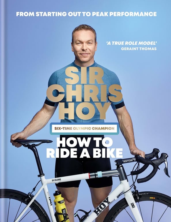 Man in cycling gear holding a white road bike against a blue background