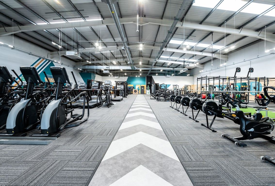 PureGym Newbury: Rows of treadmills, ellipticals, weights, benches, and exercise bikes in a modern gym setting.