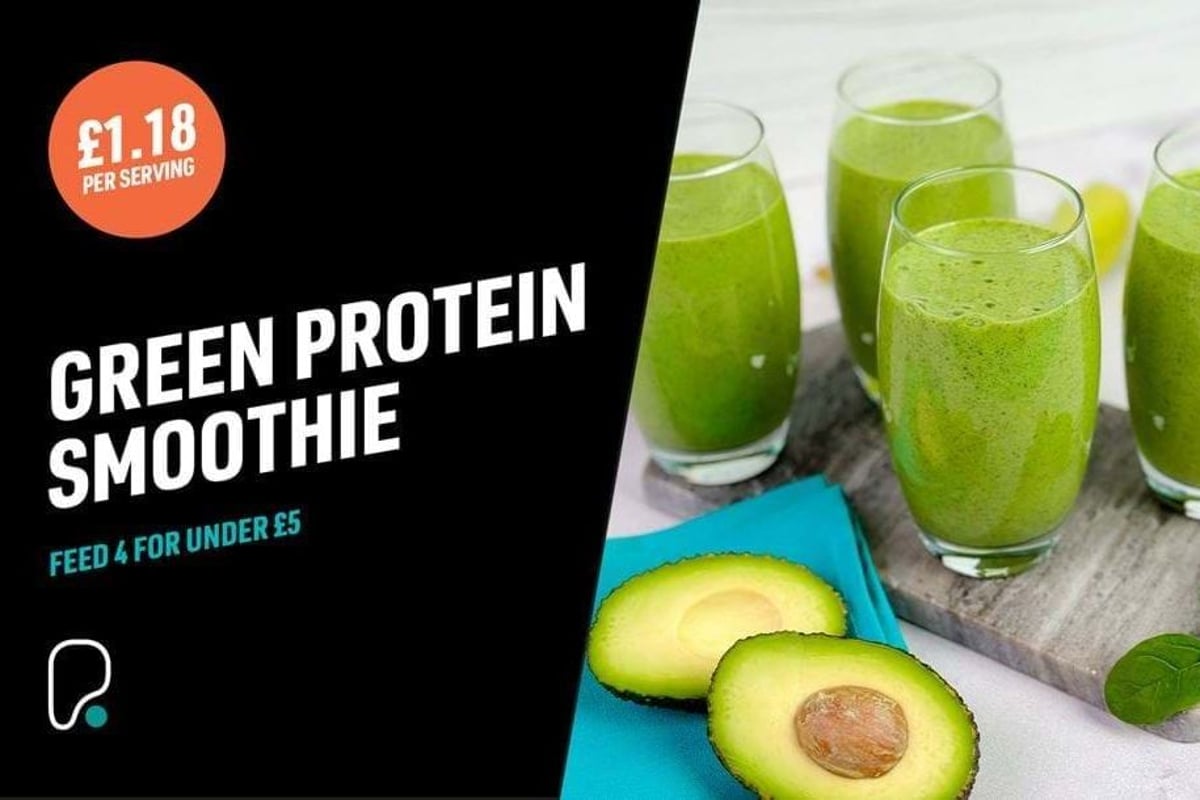 Four glasses of green smoothie on a wooden board with halved avocado and spinach leaves