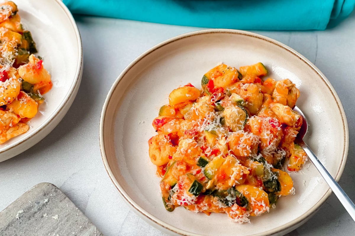 Gnocchi with chicken and vegetables in creamy tomato sauce topped with grated cheese