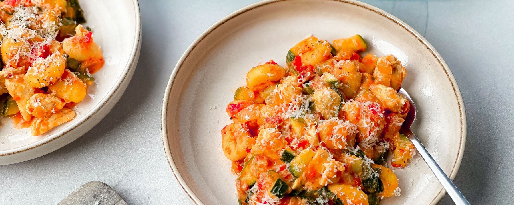 Gnocchi with chicken and vegetables in creamy tomato sauce topped with grated cheese