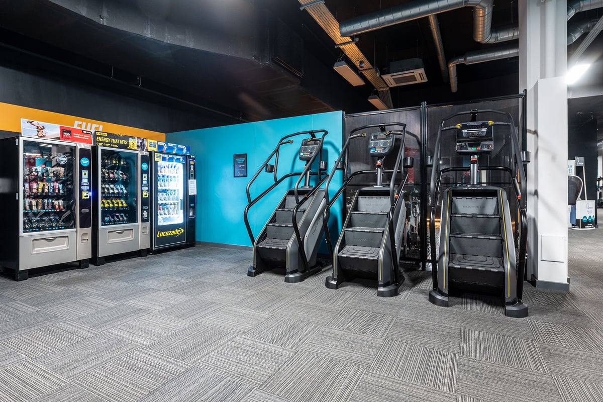 PureGym Norwich Castle Mall: Rows of treadmills, vending machines, and turf area for functional training.