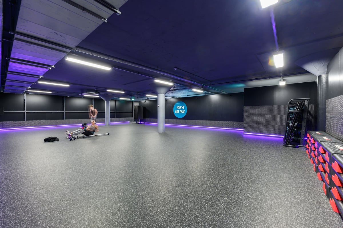 PureGym Nottingham Basford: Gym studio with weight bench, resistance bands, rubberized flooring, and purple-lit ceiling.