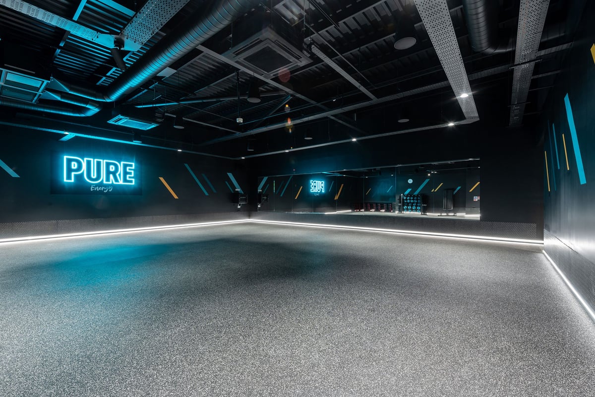 PureGym Nottingham West Bridgford: Neon-lit futuristic gym studio with textured flooring and "PURE" signage.