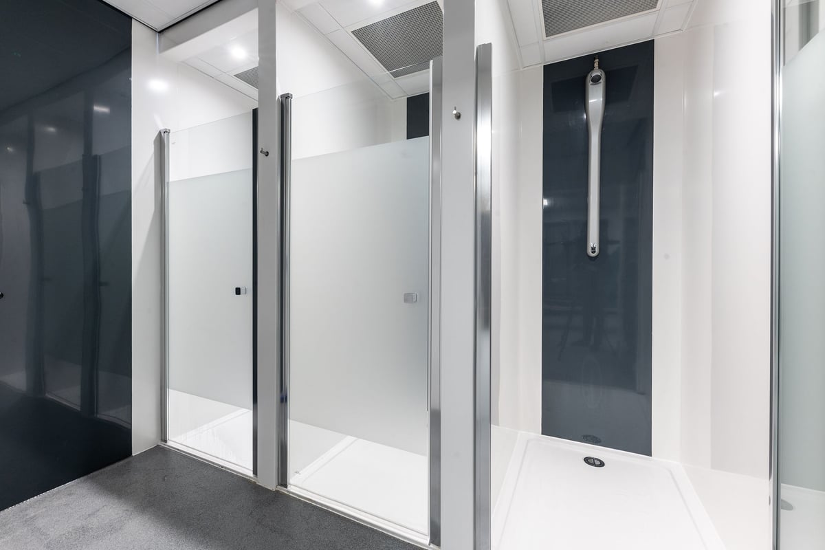 PureGym Dewsbury: Shower stalls with glass doors and tiled floors.