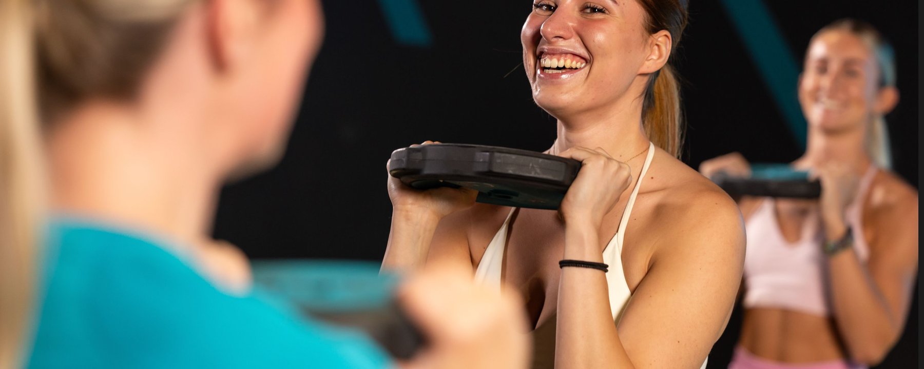 Feel PureGym Good: smiling woman lifting weight plate