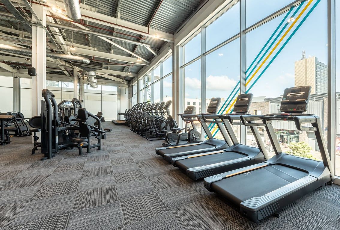 PureGym Newport Wales: Rows of treadmills, stationary bikes, and colourful weight equipment in a modern gym space.