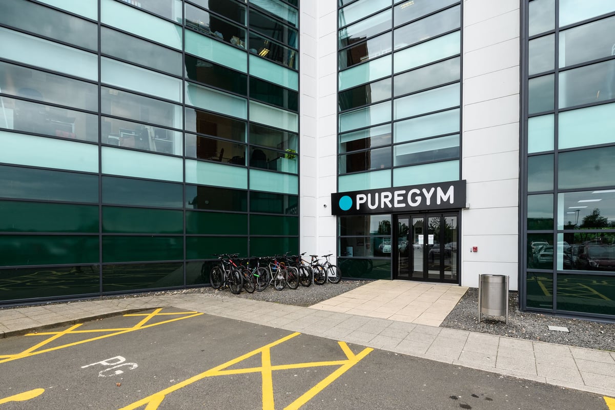 PureGym Newcastle Longbenton: Bicycle racks outside modern office building with PureGym signage.
