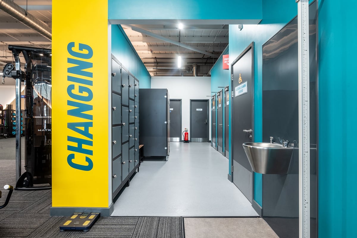 PureGym Bideford: Rows of industrial lockers or changing room cubicles and a long hallway.