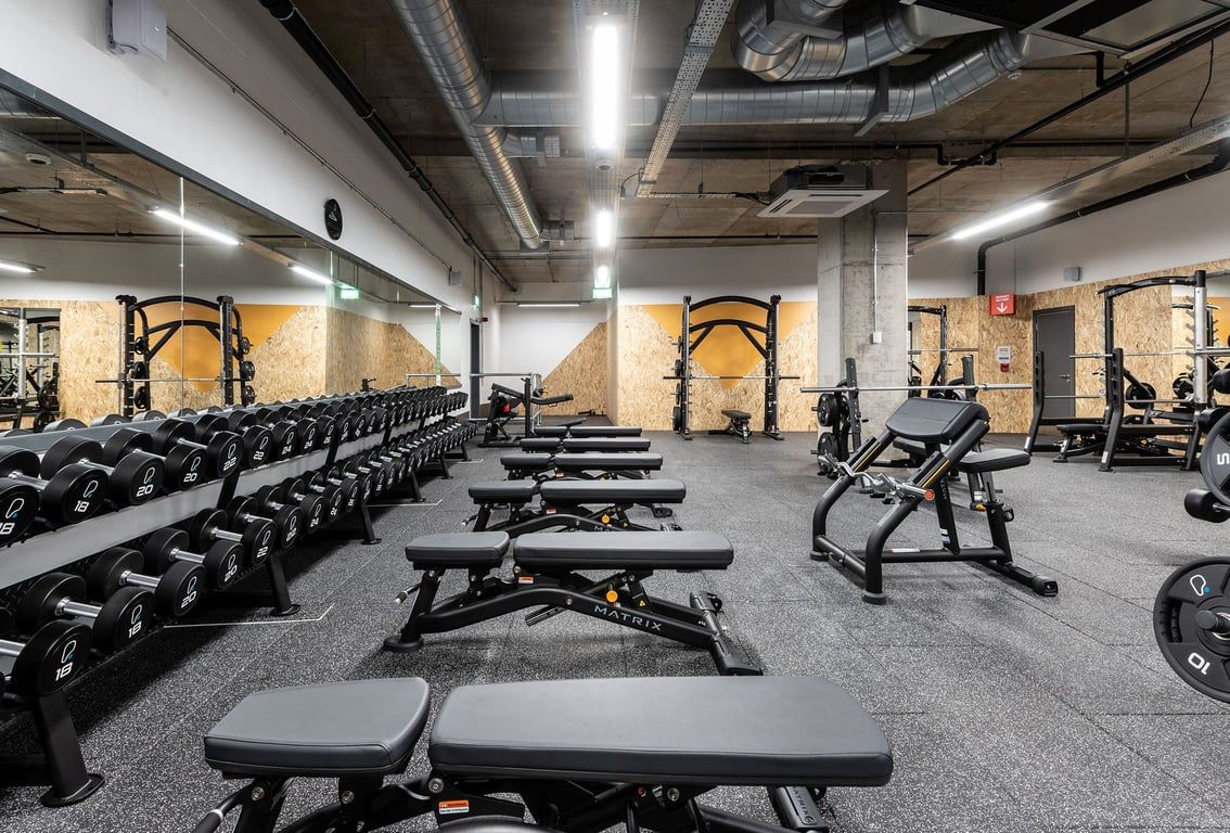 PureGym London Hoxton: Rows of weight benches, dumbbells, weight racks, and resistance machines on rubberized flooring.