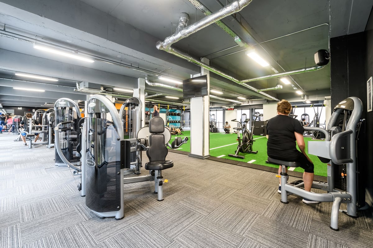 PureGym London Lambeth: Weight machines, free weights, turf area, and mirrored walls in a dimly lit gym interior.