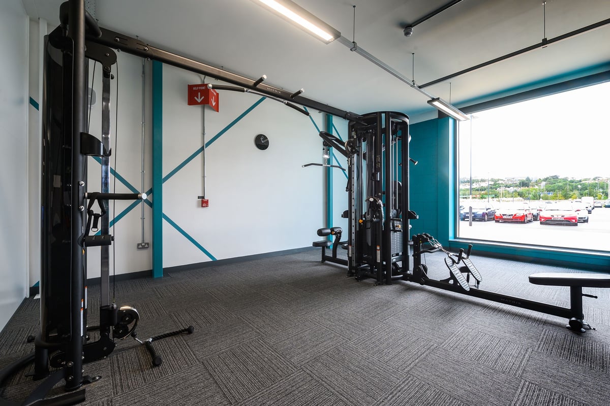 PureGym Barnstaple: Weightlifting racks, resistance machines, benches, and rubberised flooring in a brightly-lit gym studio.