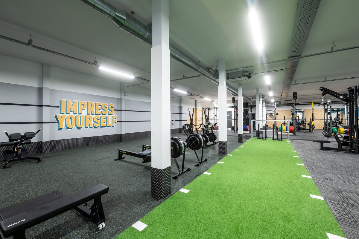 PureGym Derby Kingsway Retail Park: Weight benches, squat racks, free weights, turf area, and motivational wall text.