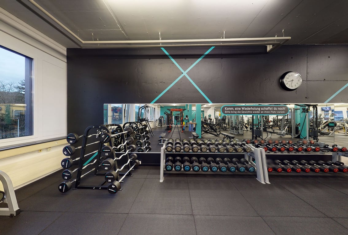 PureGym Wettingen: Reihen von Hantelablagen, Hantelbänken und Spiegelwänden.