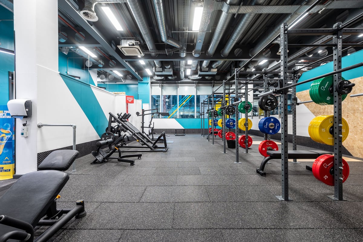 PureGym Manchester Spinningfields: Gym studio with racks, weight plates in various colours, benches, and rubberized floors.