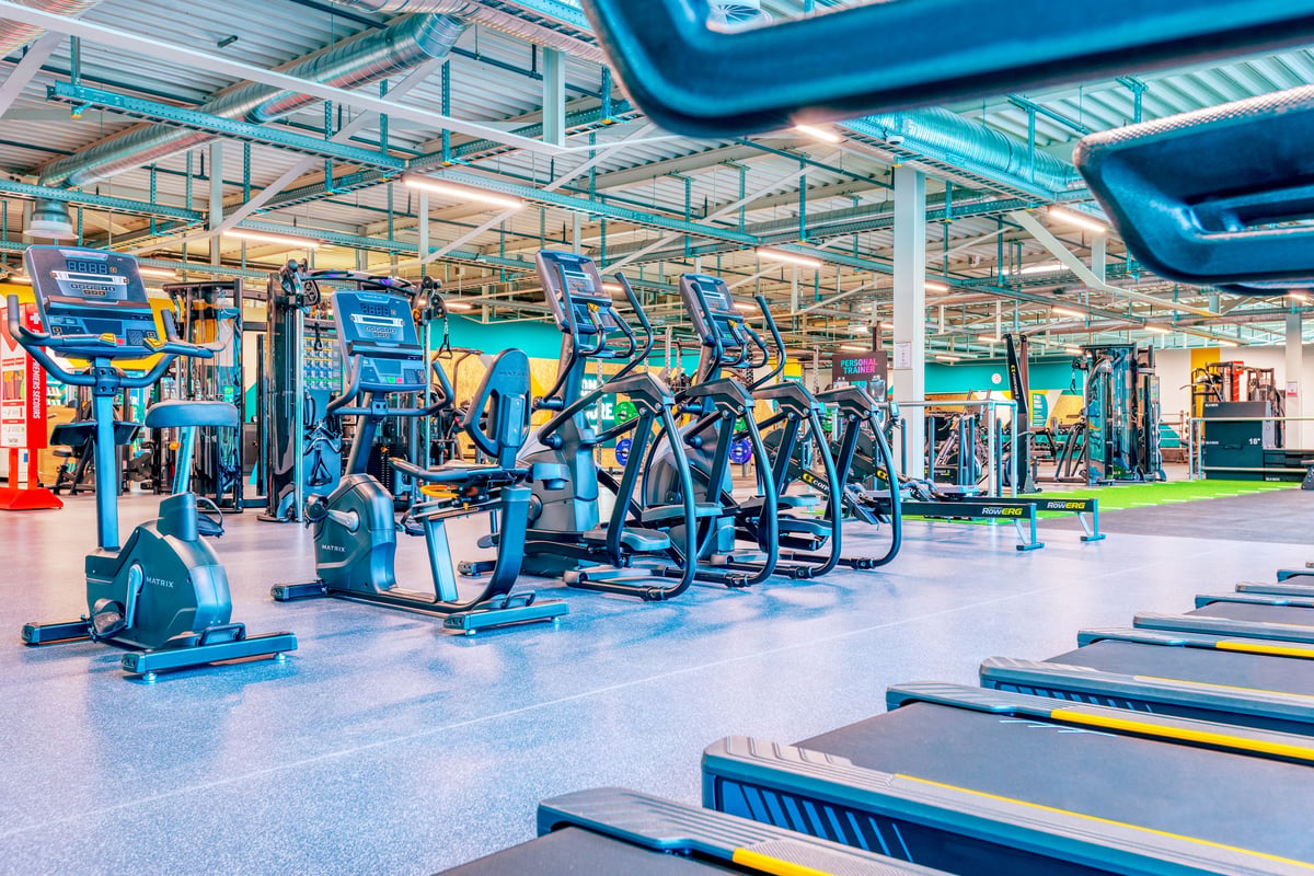 PureGym Martigny: Kardiogeräte, Kraftstationen und Bänke in einem hellen Fitnessstudio.