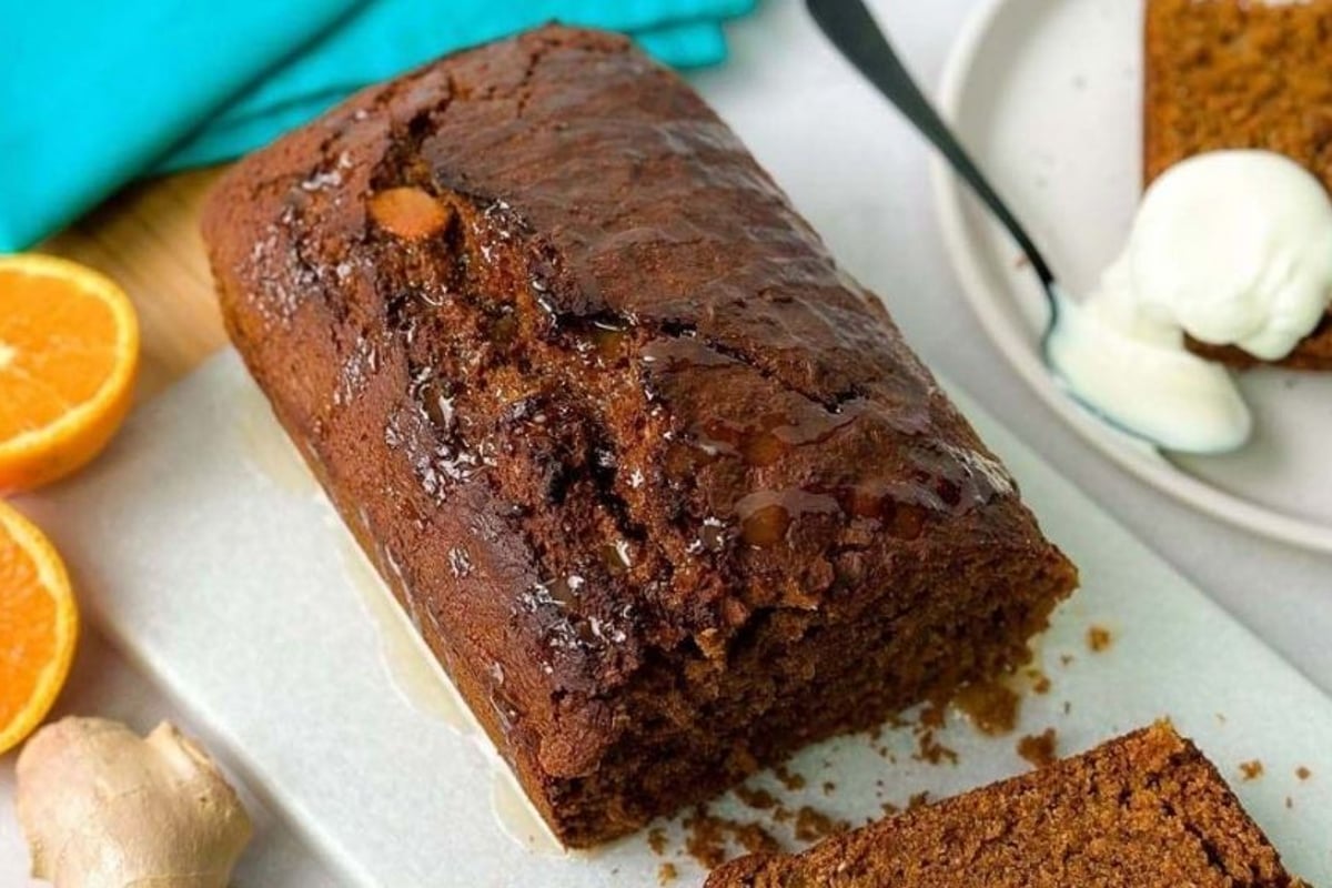 Chocolate loaf cake with syrup, orange halves, ginger root, and a plate with cake