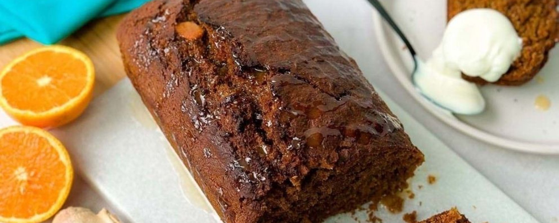 Chocolate loaf cake with syrup, orange halves, ginger root, and a plate with cake