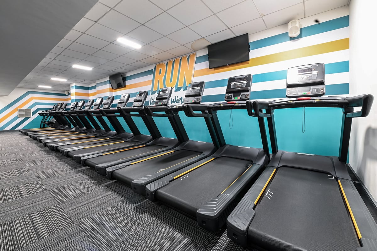 PureGym London Piccadilly: Rows of treadmills in a turquoise and yellow themed gym interior.