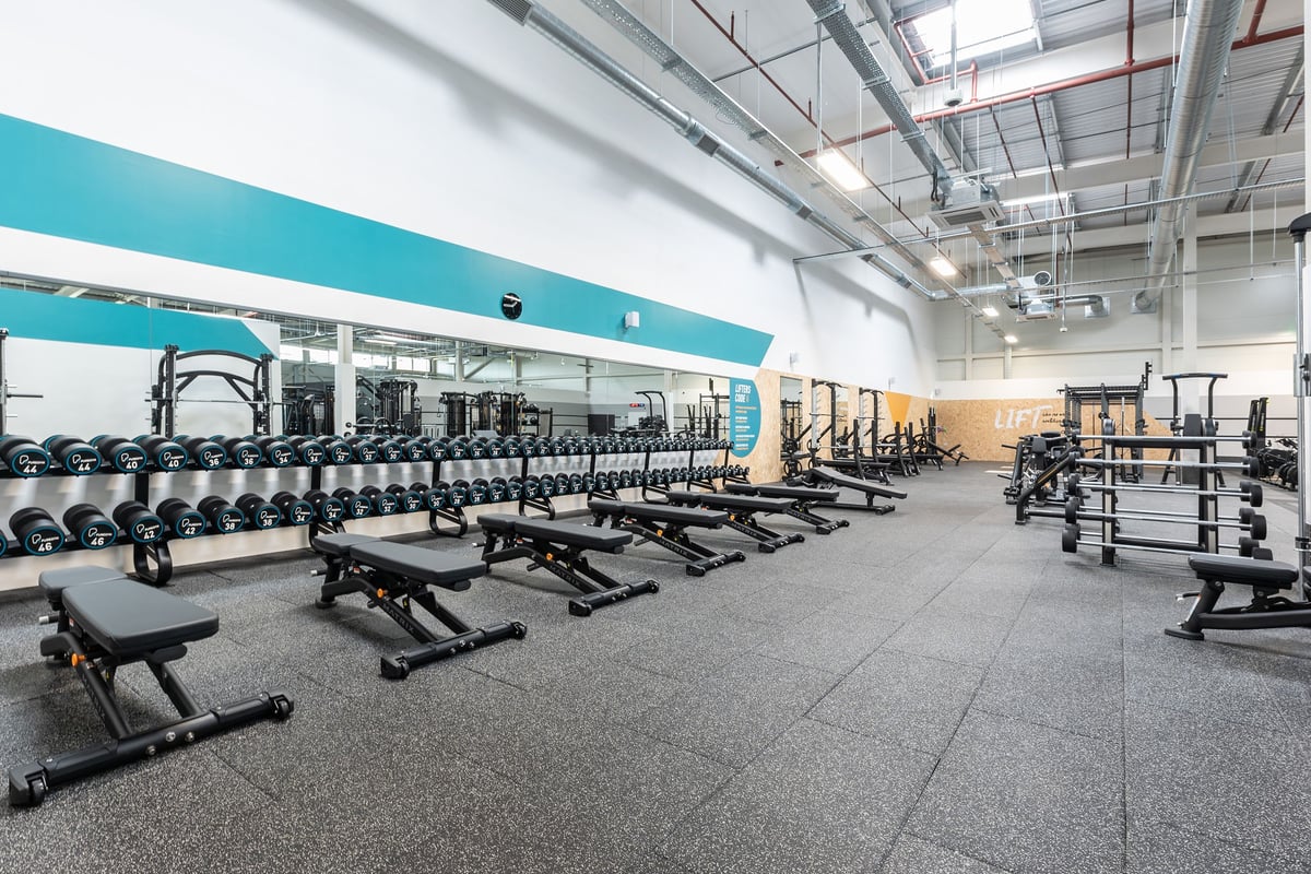 PureGym Nottingham Colwick: Rows of benches, free weight stands and racks with dumbbell sets lining the rubberized floor.