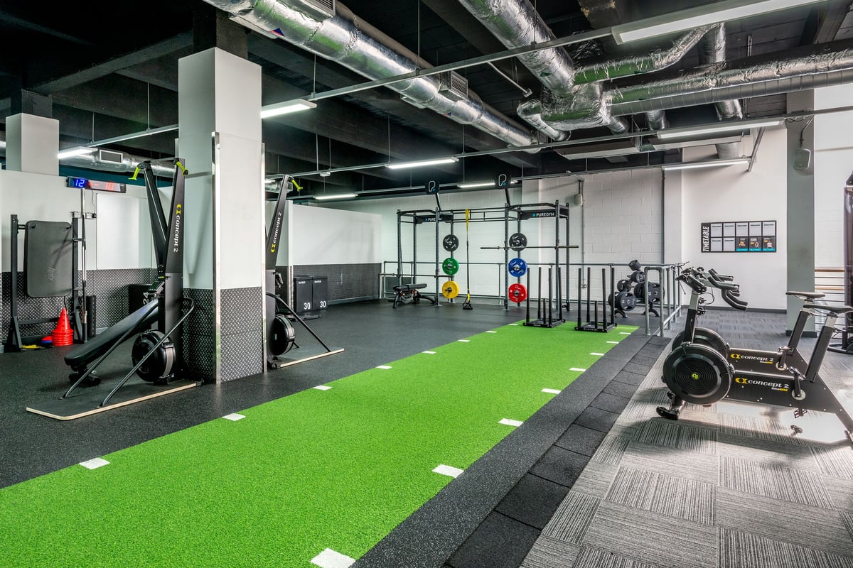 PureGym Manchester Market Street: Functional training area with turf, squat racks, weight plates, rigs and rubberized floors.