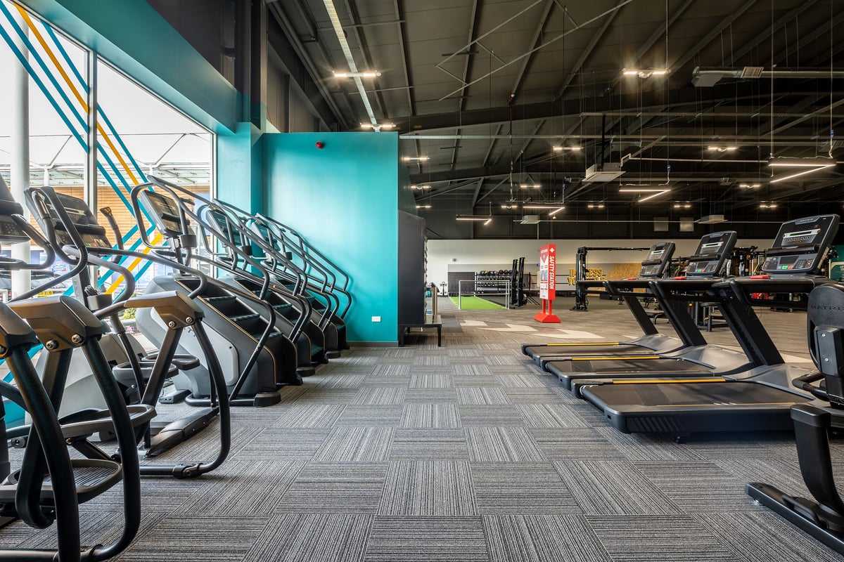 PureGym Walsall Crown Wharf: Rows of treadmills and exercise bikes, with teal accent wall and patterned flooring.