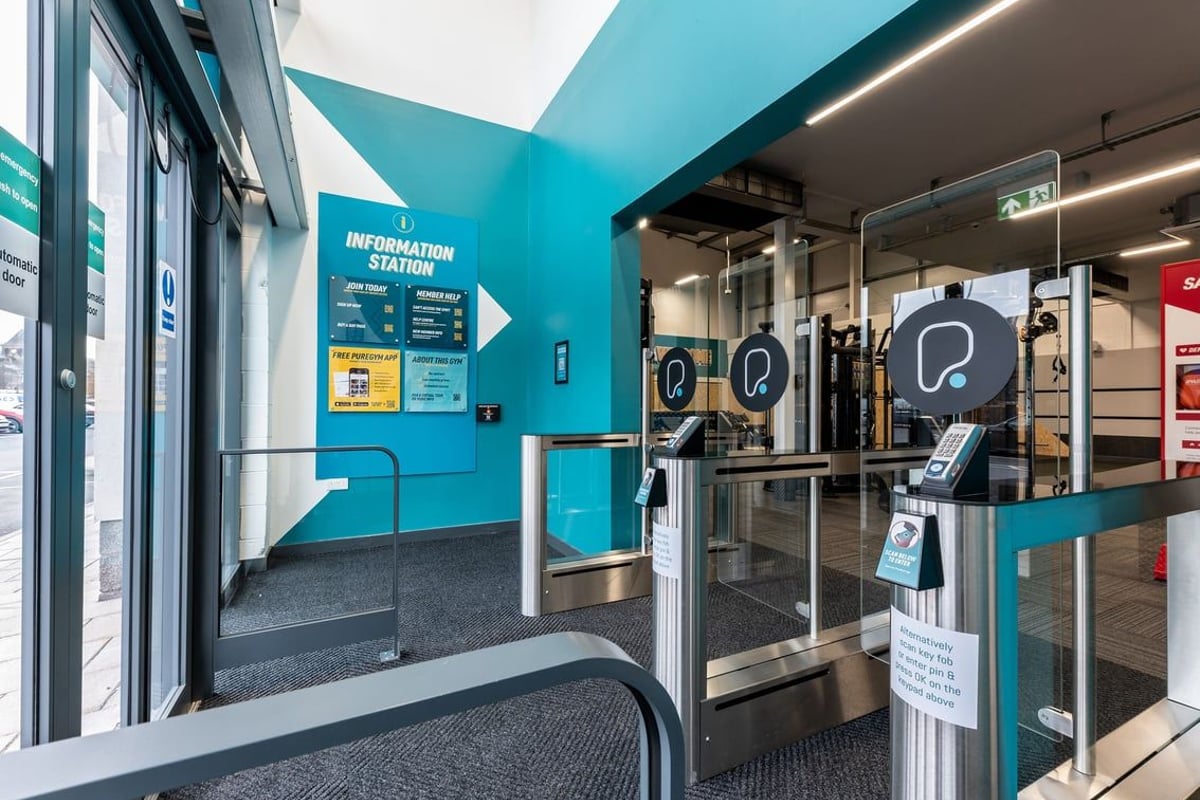 PureGym Galashiels: Entrance area with turnstiles, information signs, and self-service kiosks.