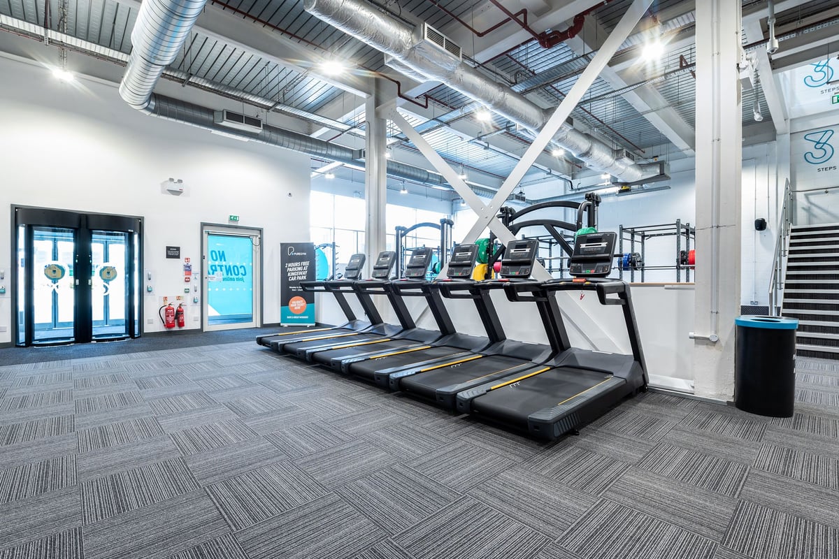 PureGym Newport Wales: Rows of treadmills, exposed ductwork, and signage indicating a gym interior.