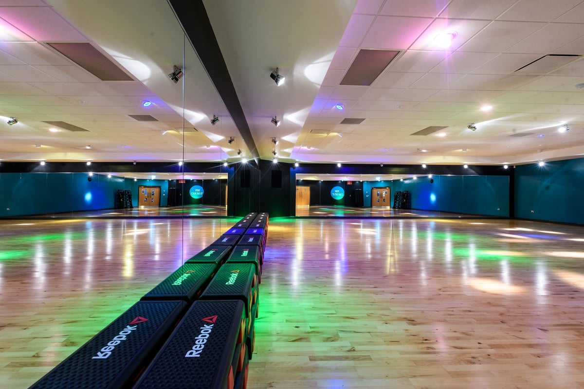 PureGym Aylesbury: Fitness studio with energising lighting, mirrors, and stacks of aerobic step platforms.