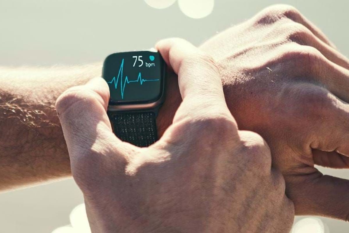 Person checking heart rate of 75 bpm on a smartwatch with a black strap.