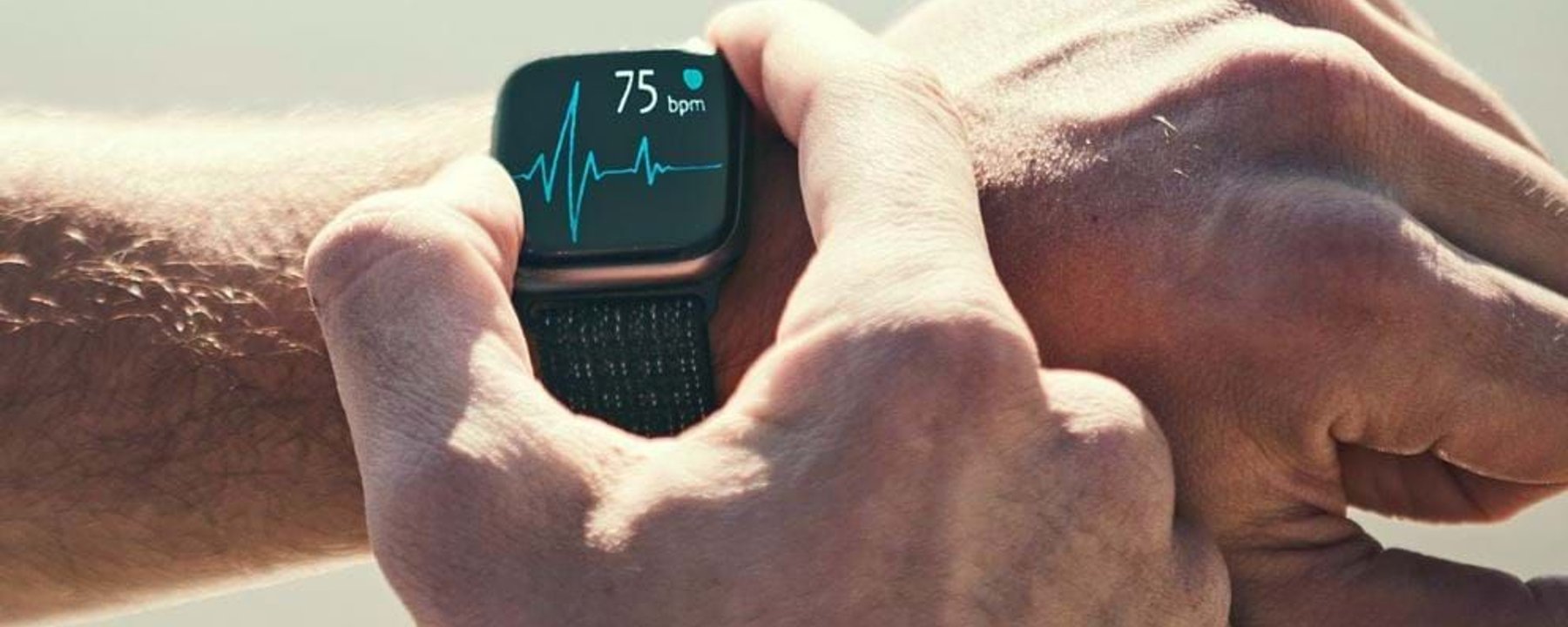 Person checking heart rate of 75 bpm on a smartwatch with a black strap.