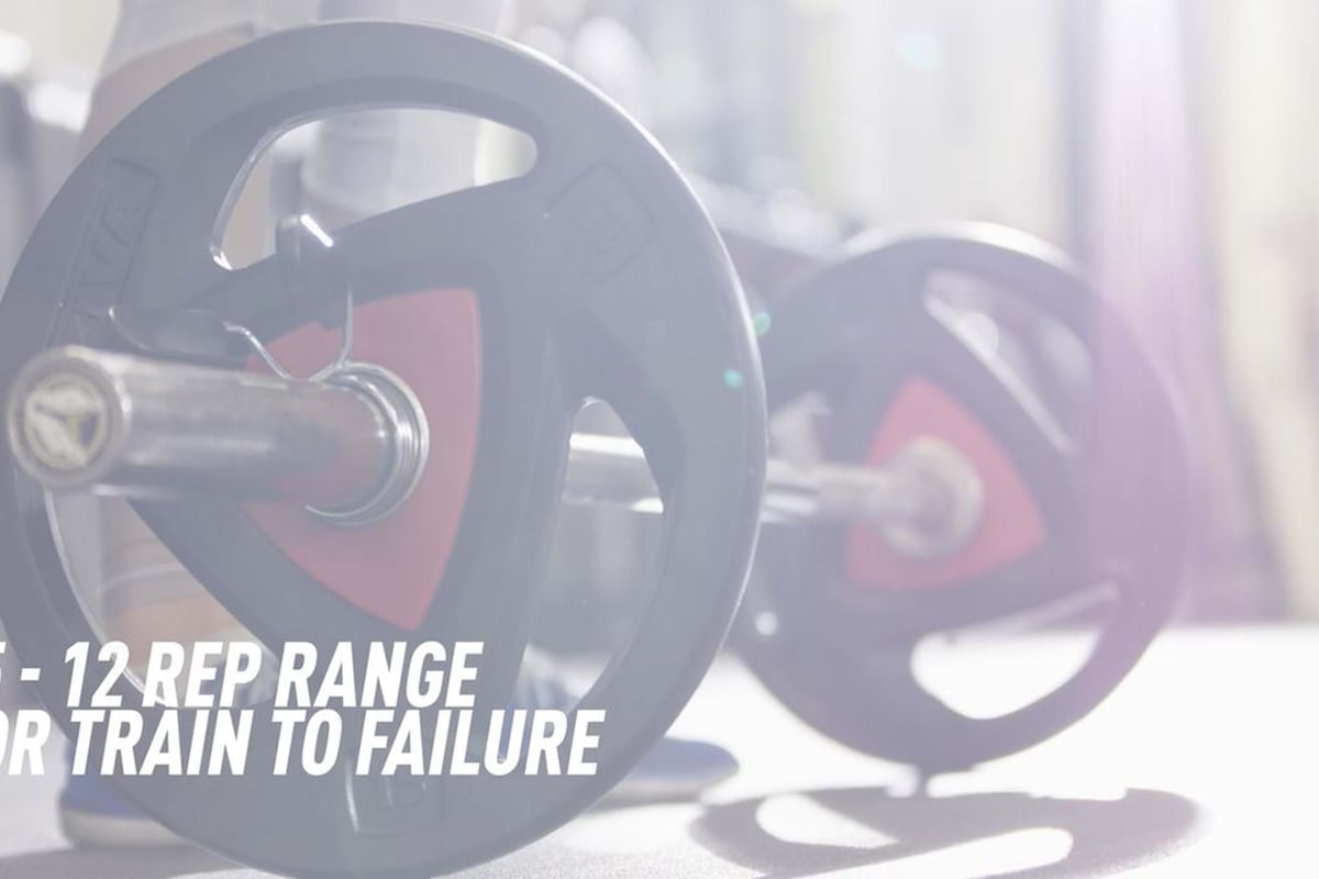 Barbell with weight plates on a gym floor with text about rep range and training to failure