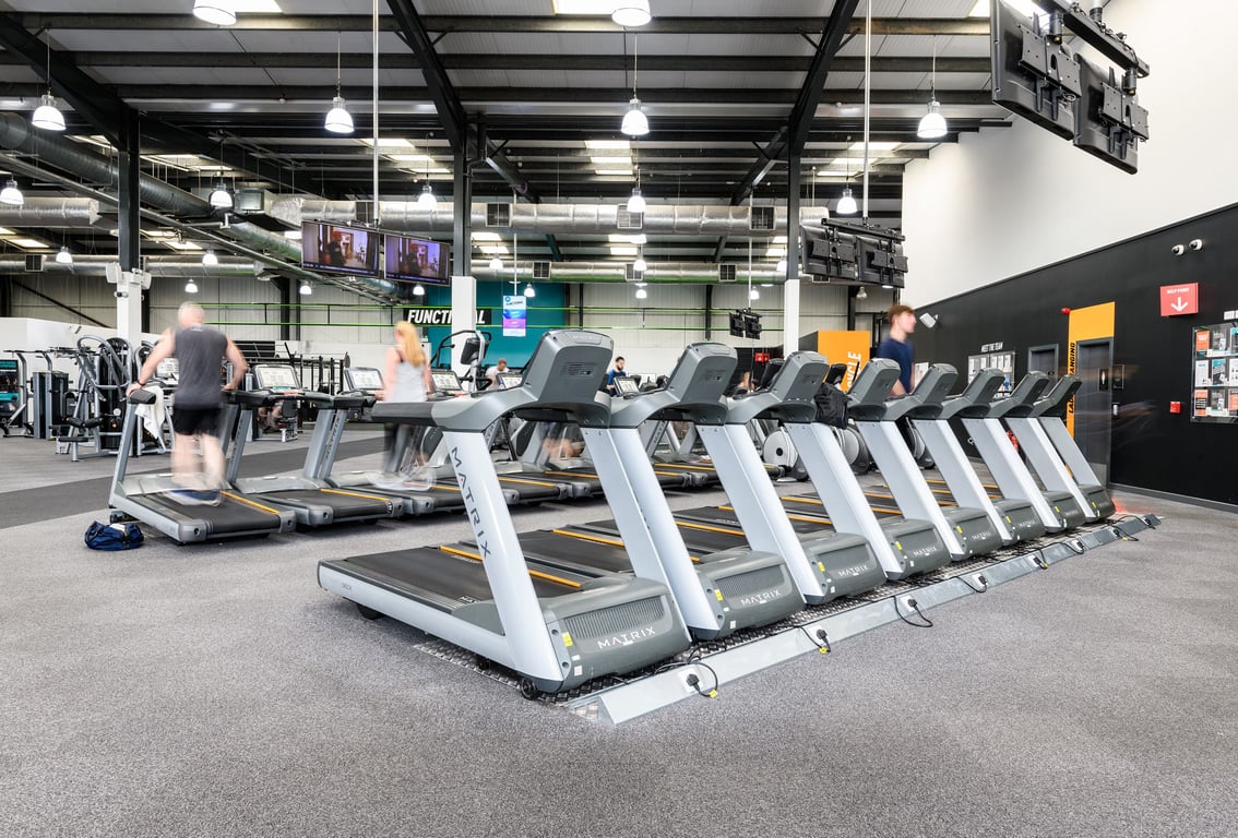 PureGym Stoke On Trent North: Rows of treadmills and other cardio machines in a bright gym interior.